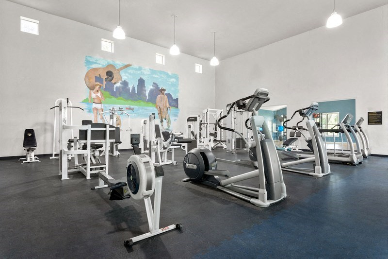 a gym with cardio equipment and a mural on the wall