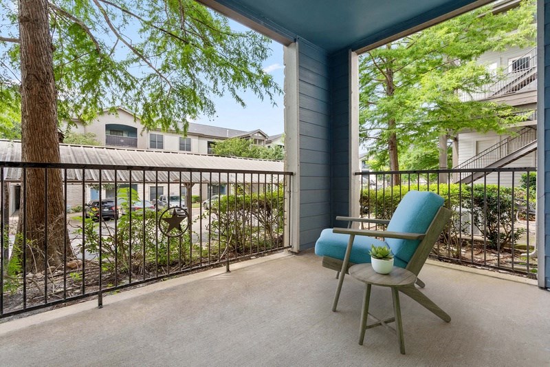 a balcony with a blue chair and a tree