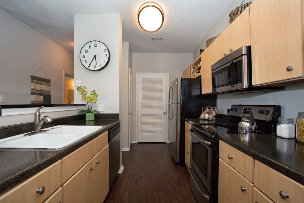 a kitchen with black counter tops and wooden cabinets