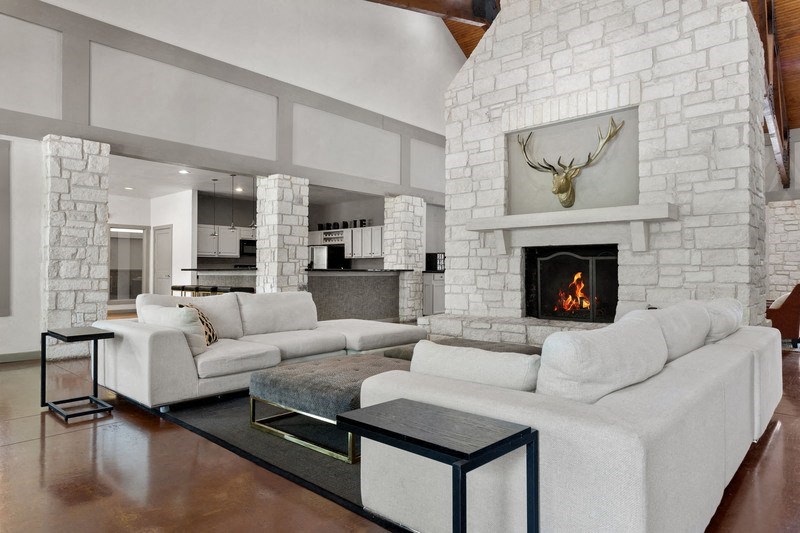a living room with white couches and a fireplace with a deer head on the mantel