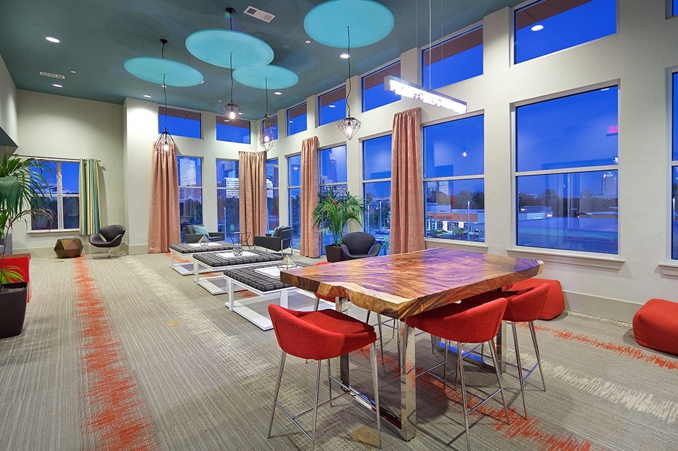 A conference room with a long table and red chairs.
