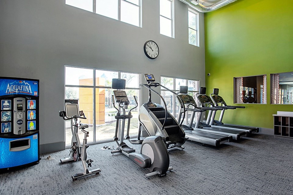 A gym with a row of treadmills, a stationary bike, and a vending machine.