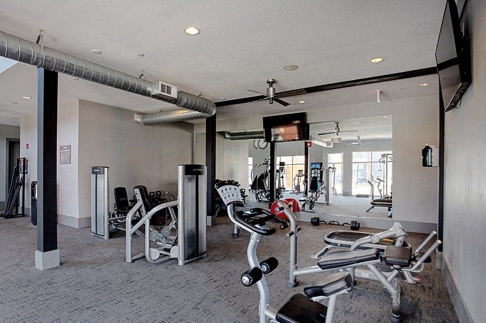 A gym with a variety of equipment including treadmills, weights, and exercise machines.