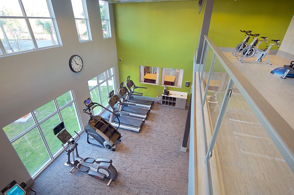 a fitness room with cardio machines and a staircase