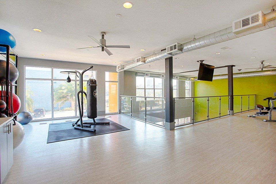 a gym with a ceiling fan and exercise equipment in a large room