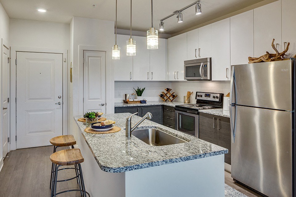A kitchen with a granite countertop and stainless steel appliances.