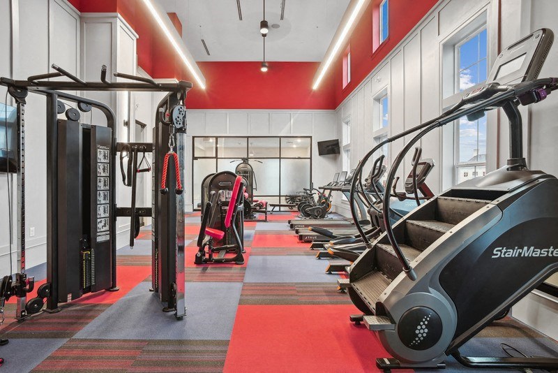 a gym with treadmills and other exercise equipment on a red floor