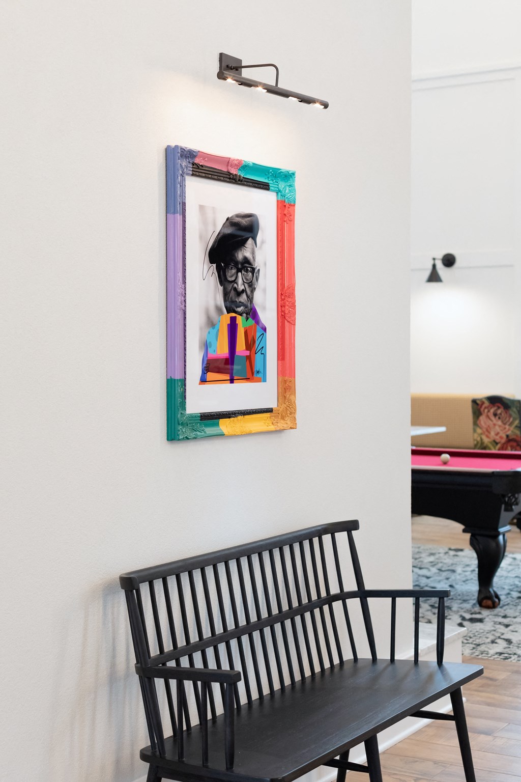 a painting hanging on a wall with a black bench in front of it