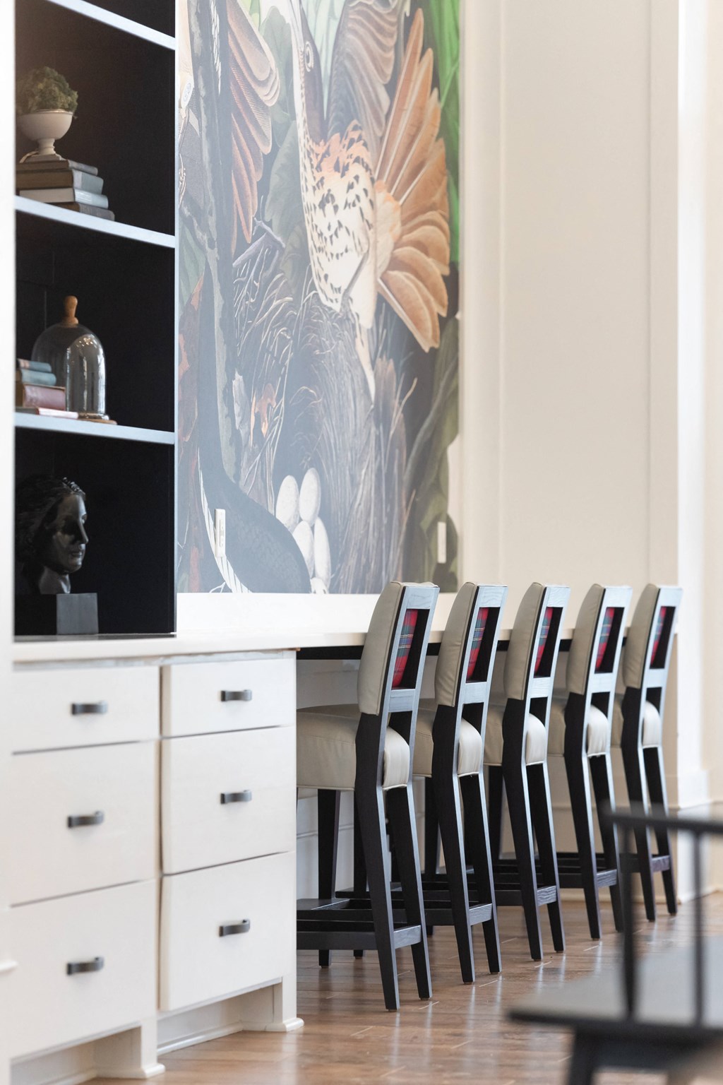 a dining room with a white table and chairs and a large painting on the wall