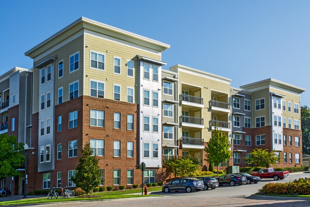 Apartment complex with a parking lot in front.