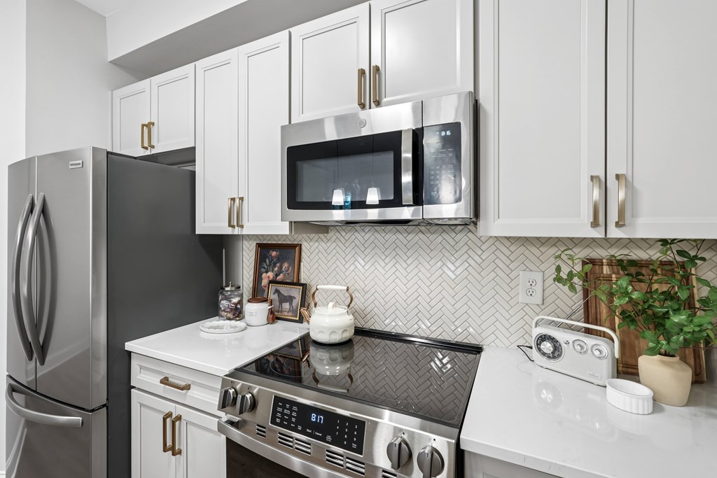 A modern kitchen with a black fridge, stove, and microwave.