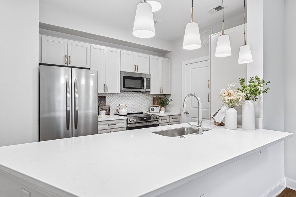 A modern kitchen with a white countertop and stainless steel appliances.
