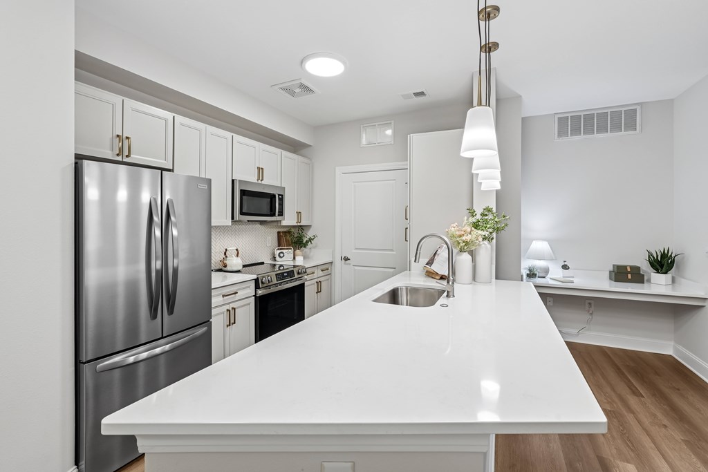 A modern kitchen with a white countertop and stainless steel appliances.