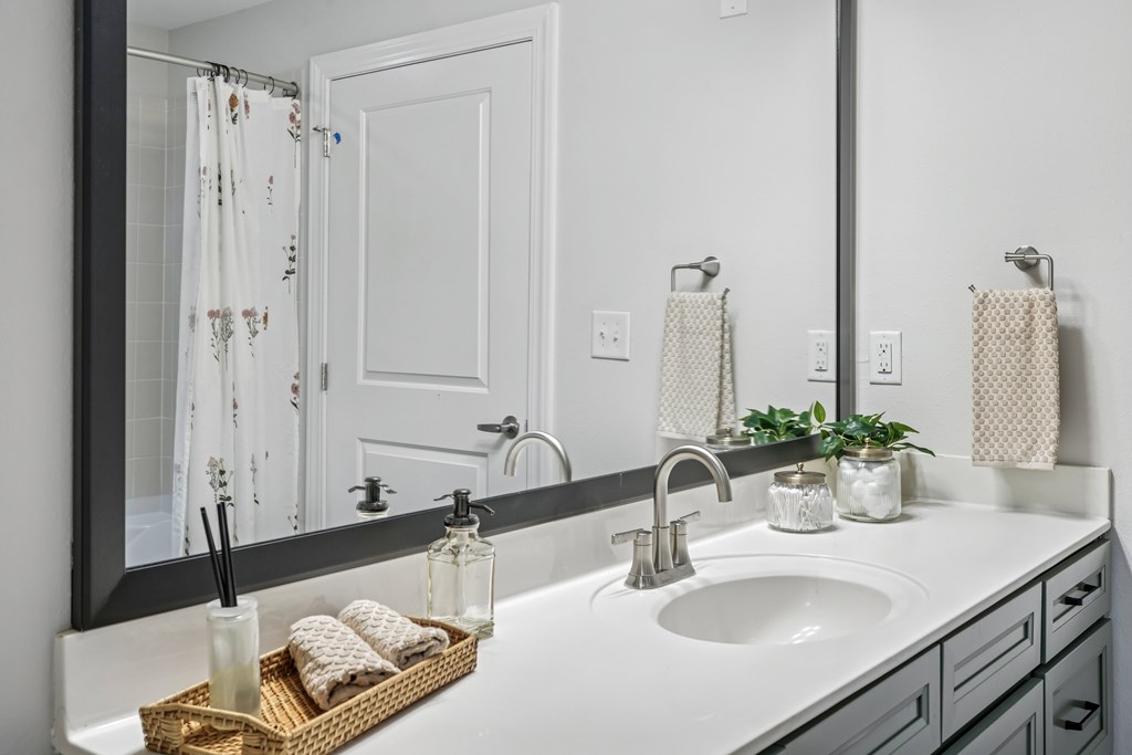 A bathroom with a white sink and a mirror above it.