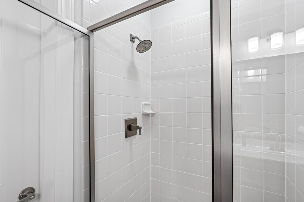 A shower head is mounted on a wall in a tiled bathroom.