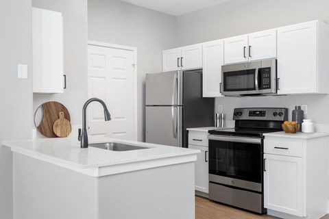 a kitchen with white cabinets and stainless steel appliances and a sink