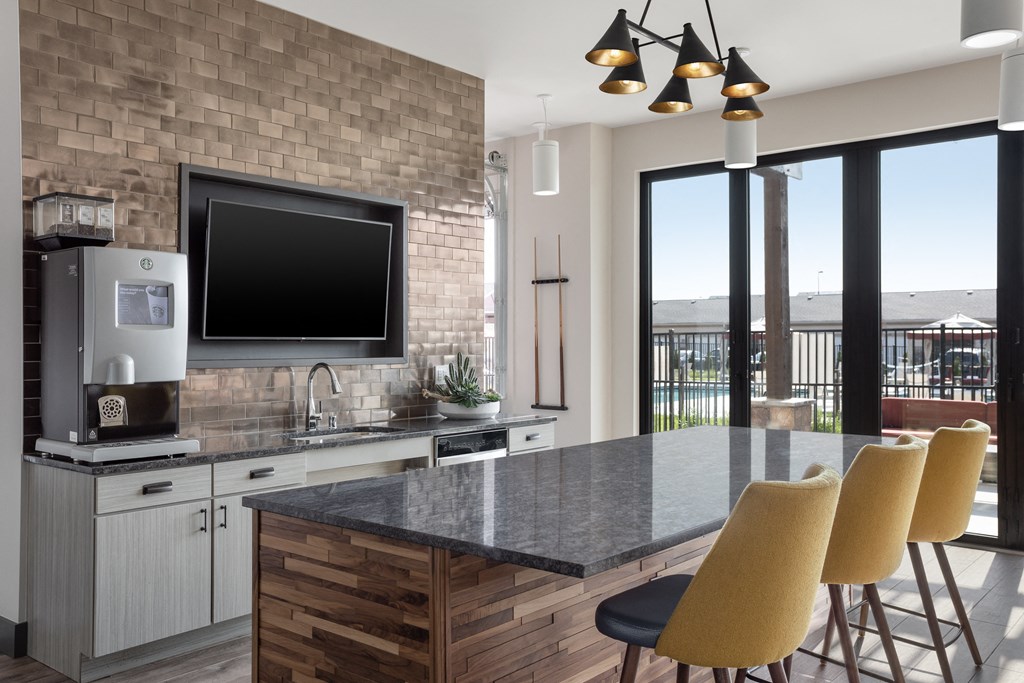 a kitchen with a counter and chairs and a television