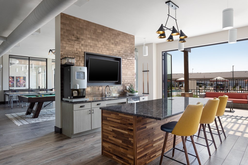 a kitchen with a bar and yellow chairs and a pool table