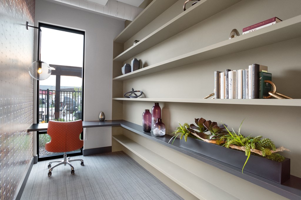 a room with a desk and a chair and shelves with plants