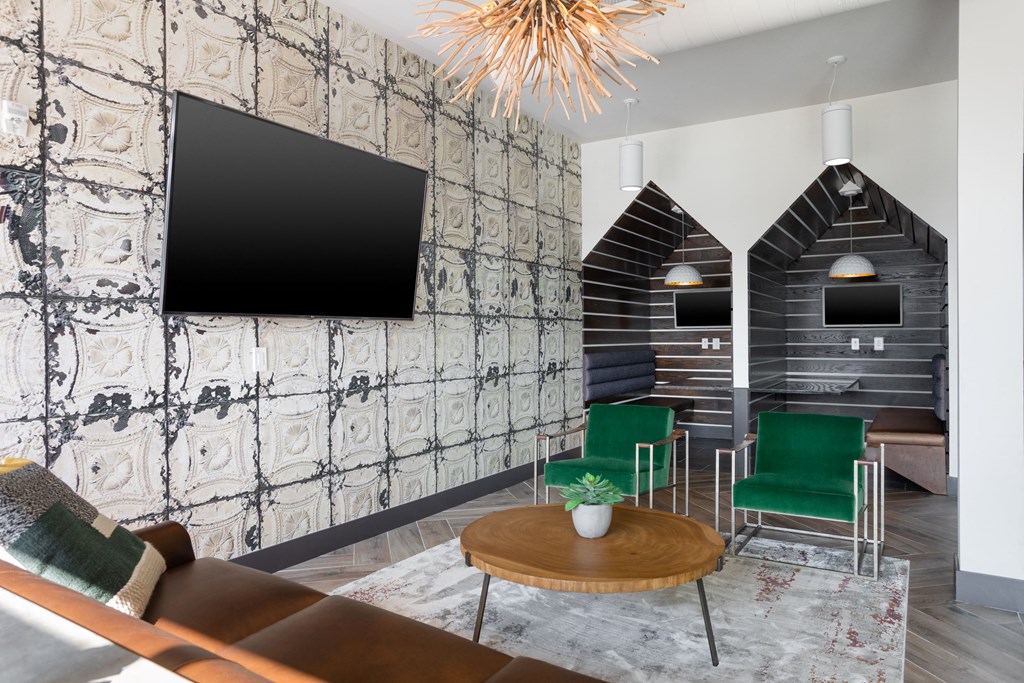 a living room with green chairs and a tv on the wall