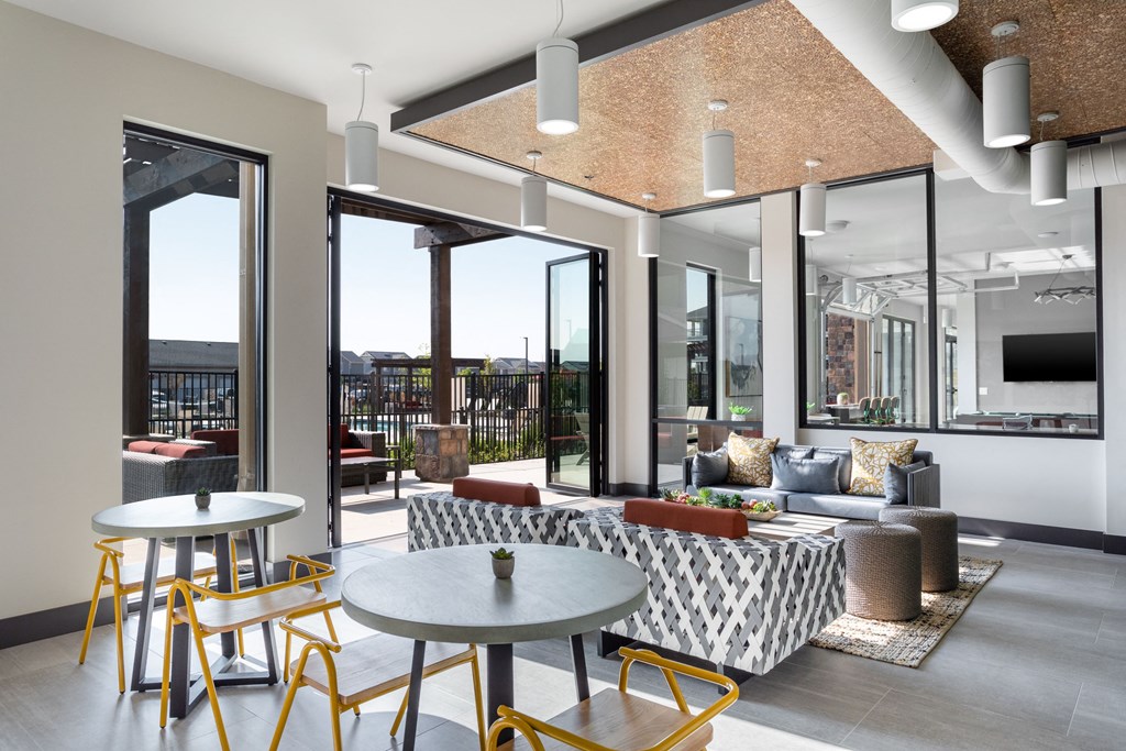 a living room with tables and chairs and large windows