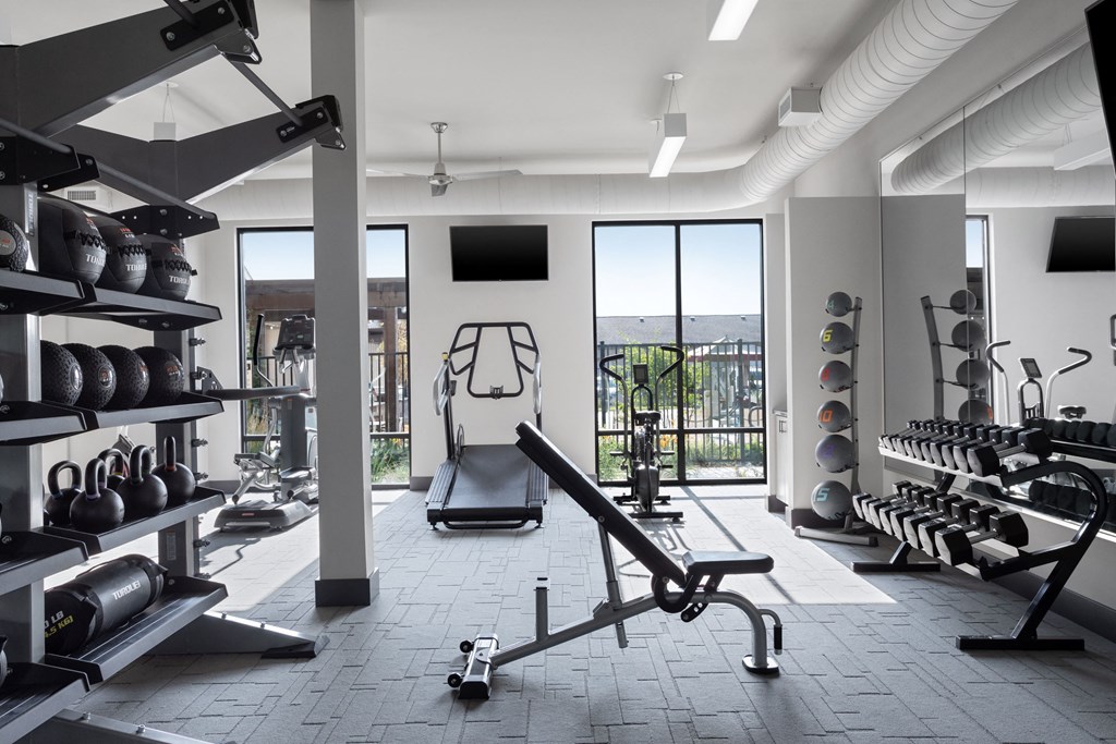 a gym with a lot of weights and cardio equipment and a window