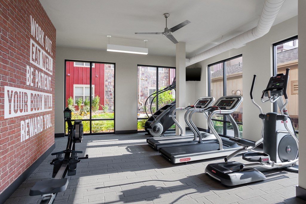 a gym with treadmills and other exercise equipment on a brick wall