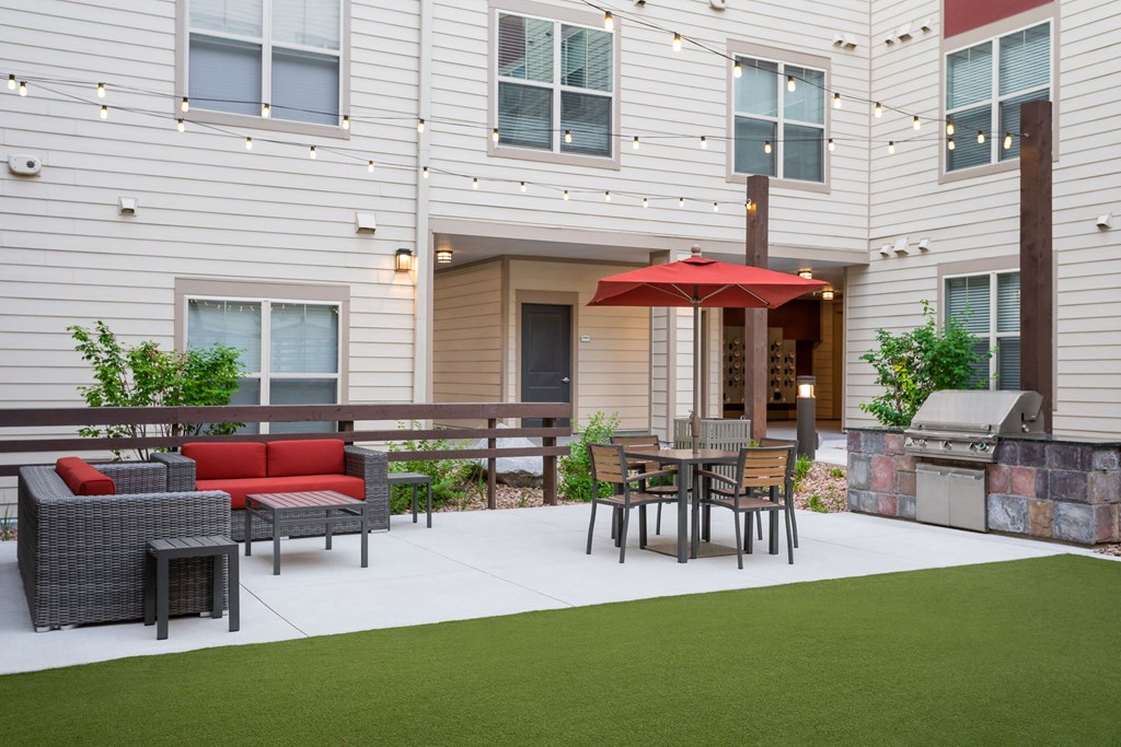a backyard patio with a table and chairs and an umbrella