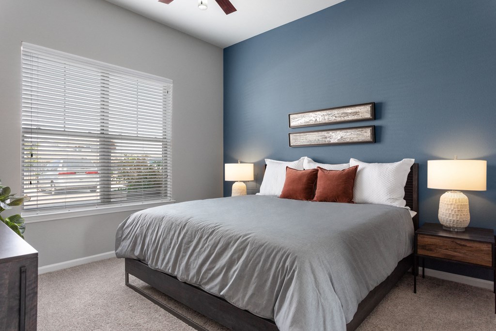 a bedroom with a large bed and a blue wall and a window