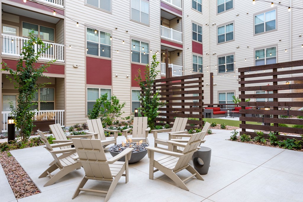 an outdoor patio with chairs and fire pit in front of an apartment building