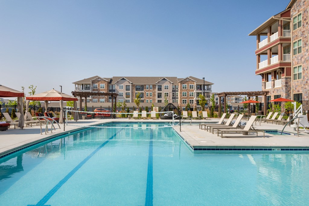a swimming pool with chairs and a building in the background