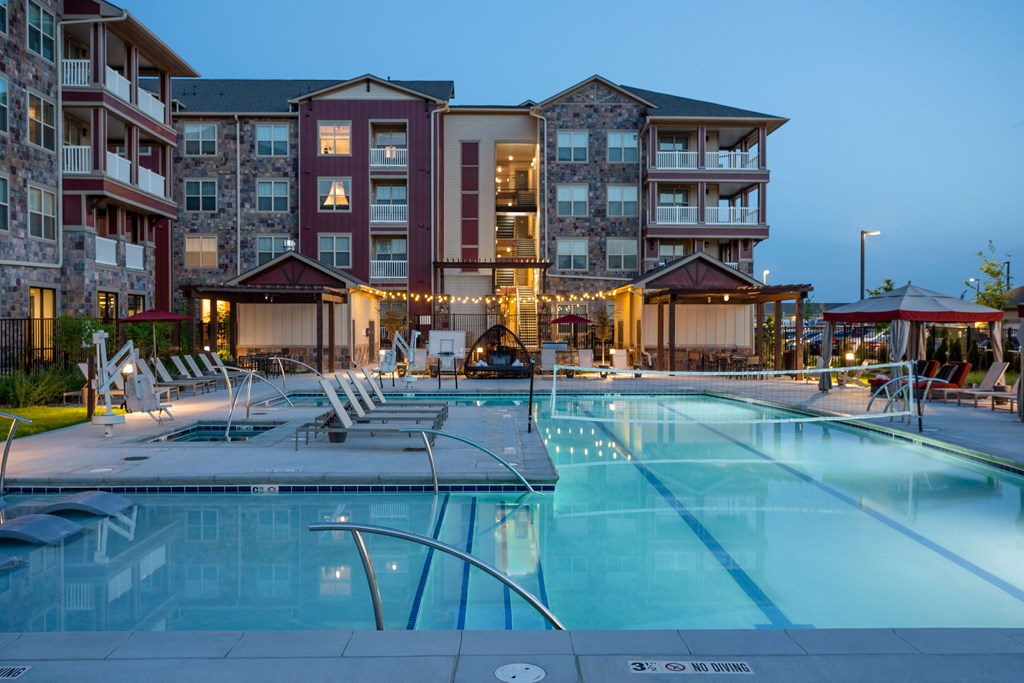 a swimming pool at night with an apartment building in the background