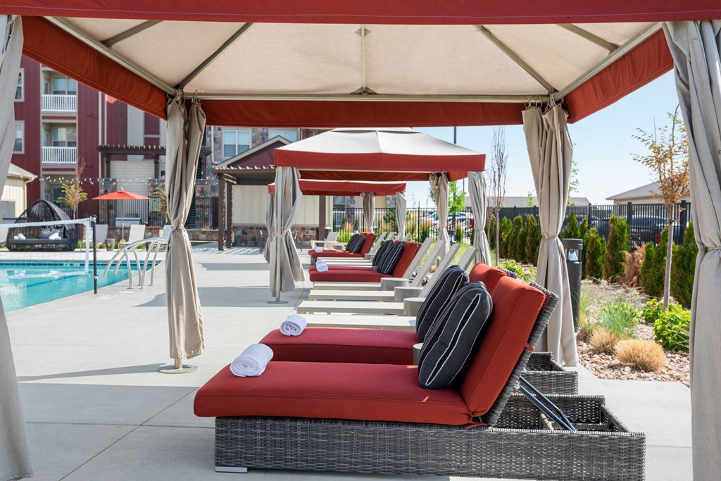 a poolside lounge area with red couches and umbrellas and a pool