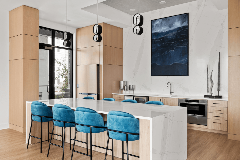 A modern kitchen with blue chairs and a large painting on the wall.