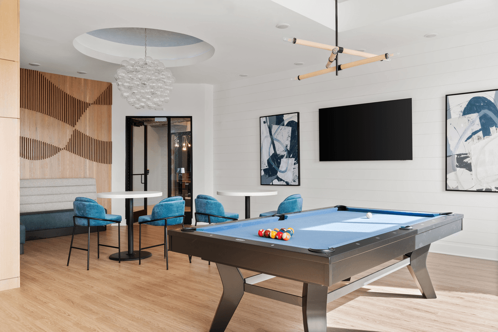 A pool table is in the middle of a room with a TV and a couch.