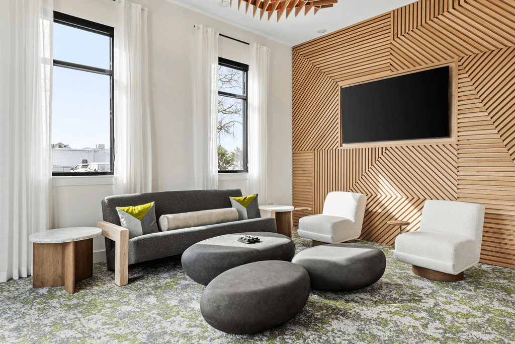 A modern living room with a grey sofa, a white armchair, and a wooden wall panel.