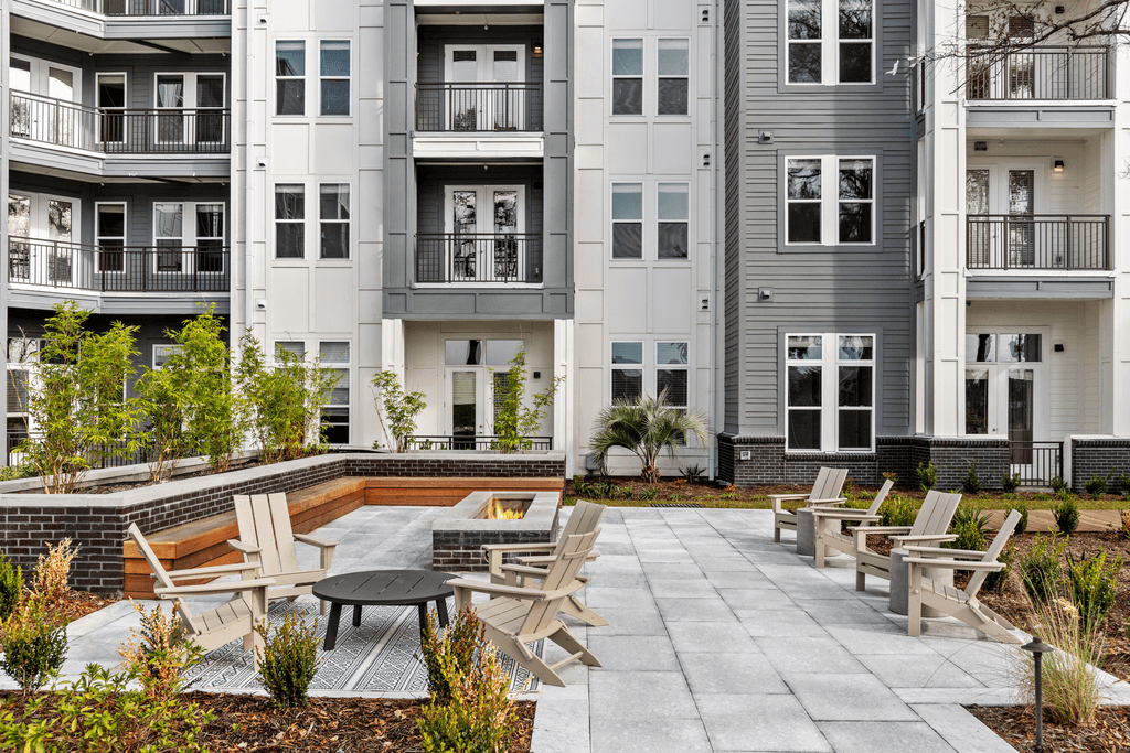 A patio with chairs and a table in front of apartment buildings.