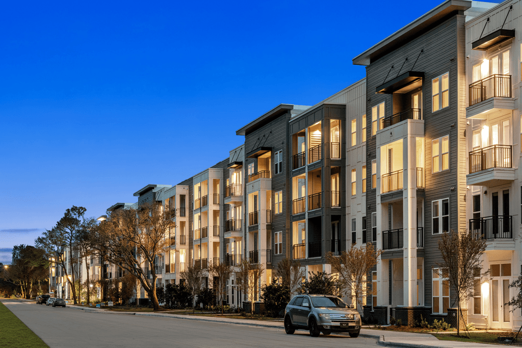 A modern apartment building with a car parked in front.