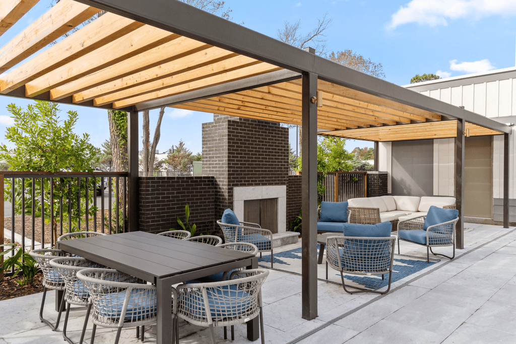 A patio with a table and chairs under a wooden roof.