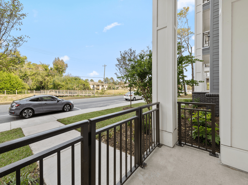 A silver car is driving down the street.