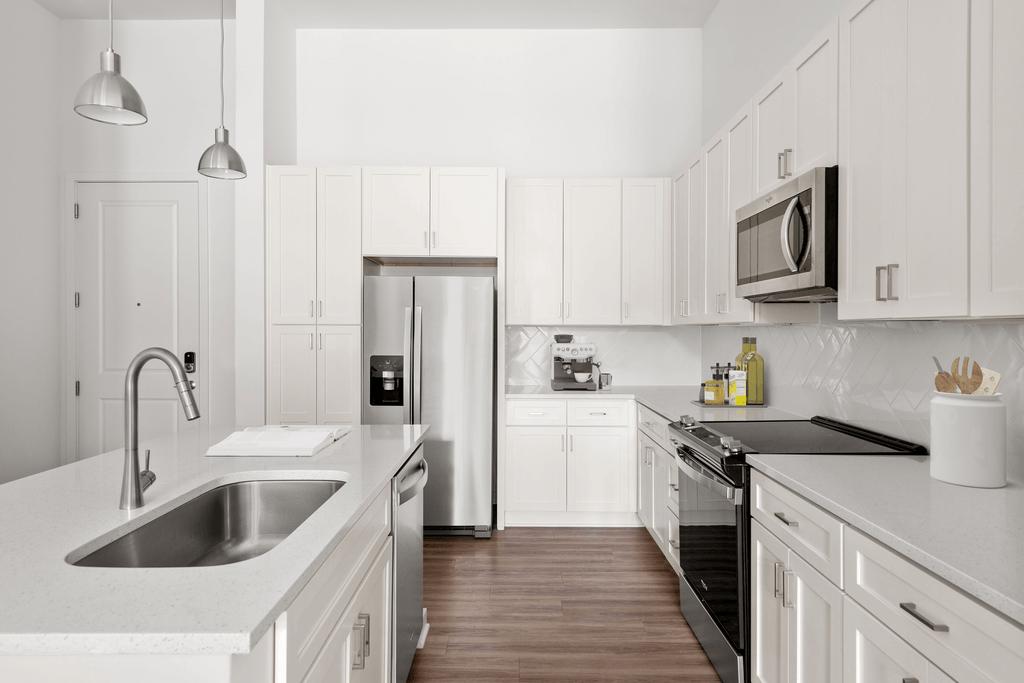 A modern kitchen with white cabinets and stainless steel appliances.