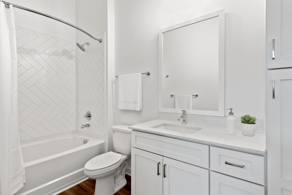 A white bathroom with a toilet, sink, and shower.