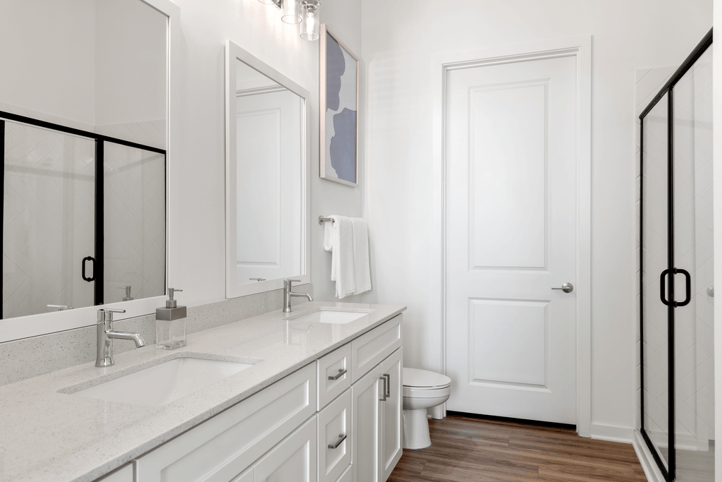 A white bathroom with a toilet, sink, and mirror.