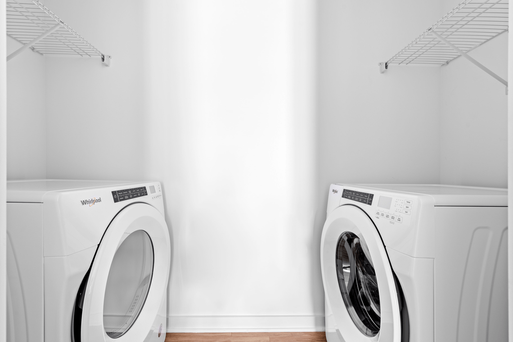 Two Whirlpool washing machines in a laundry room.