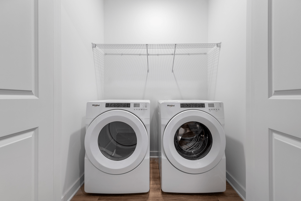 Two white front load washing machines in a laundry room.