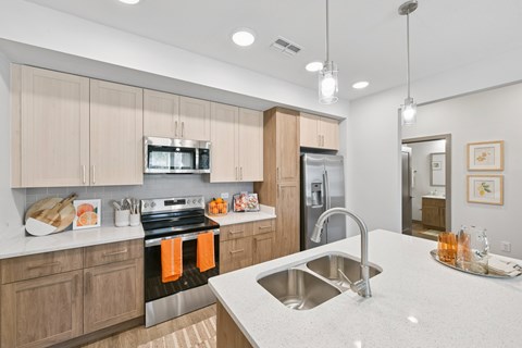 A modern kitchen with a stainless steel sink and wooden cabinets.