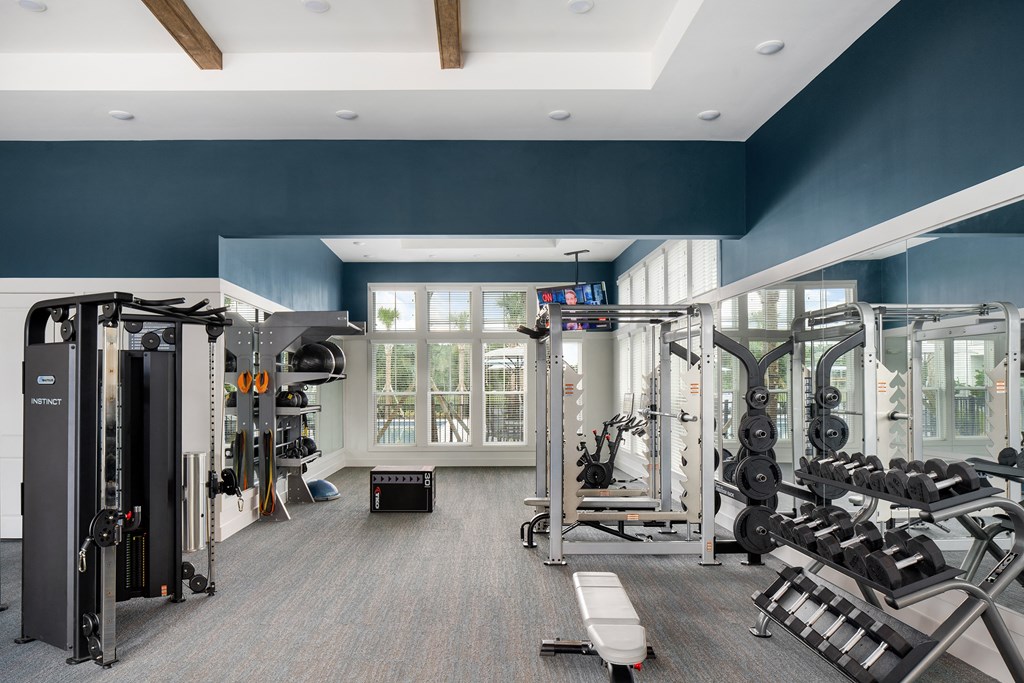 a large fitness room with cardio equipment and windows