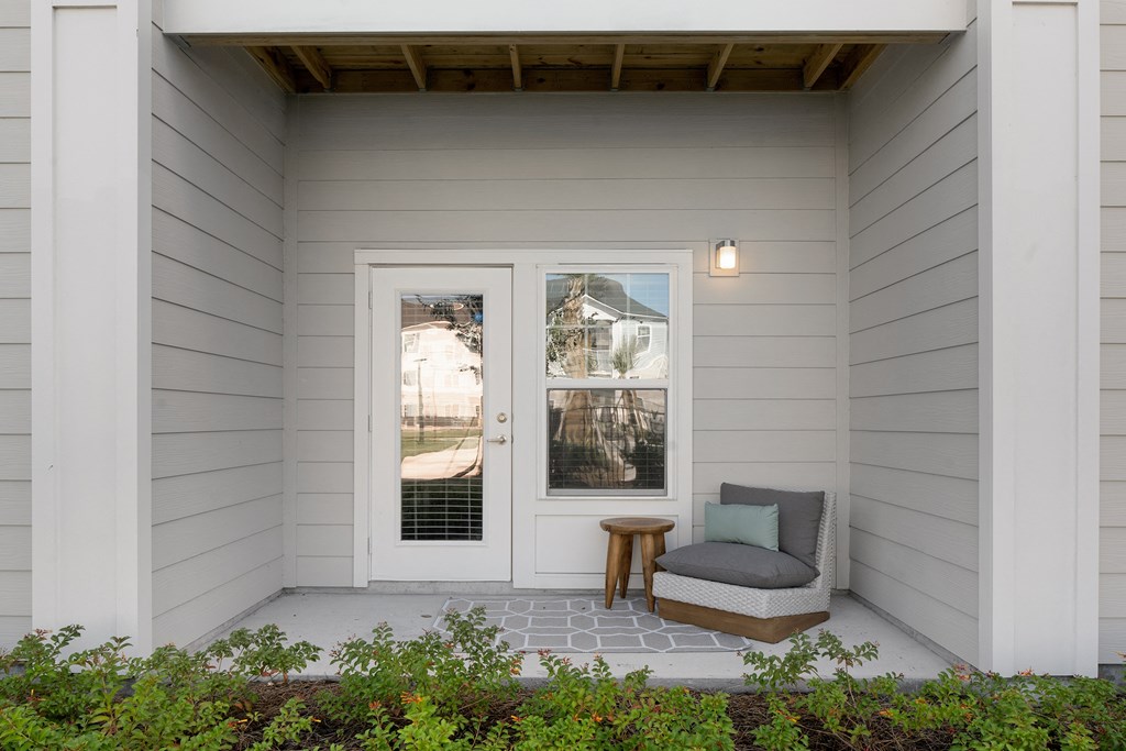 a small porch with a chair and a stool