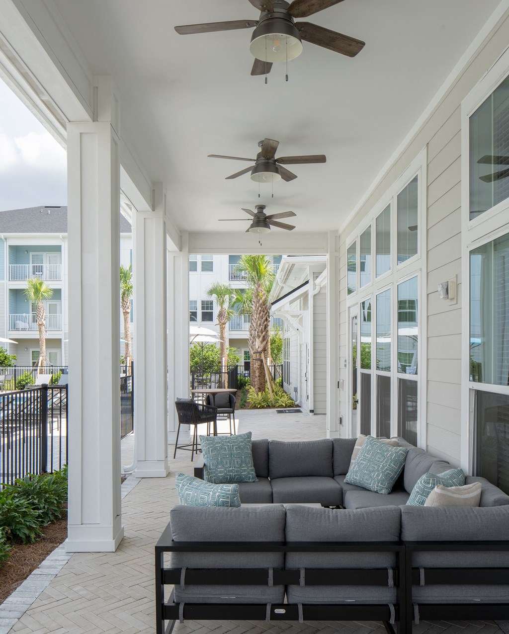 a screened in porch with a couch and ceiling fans