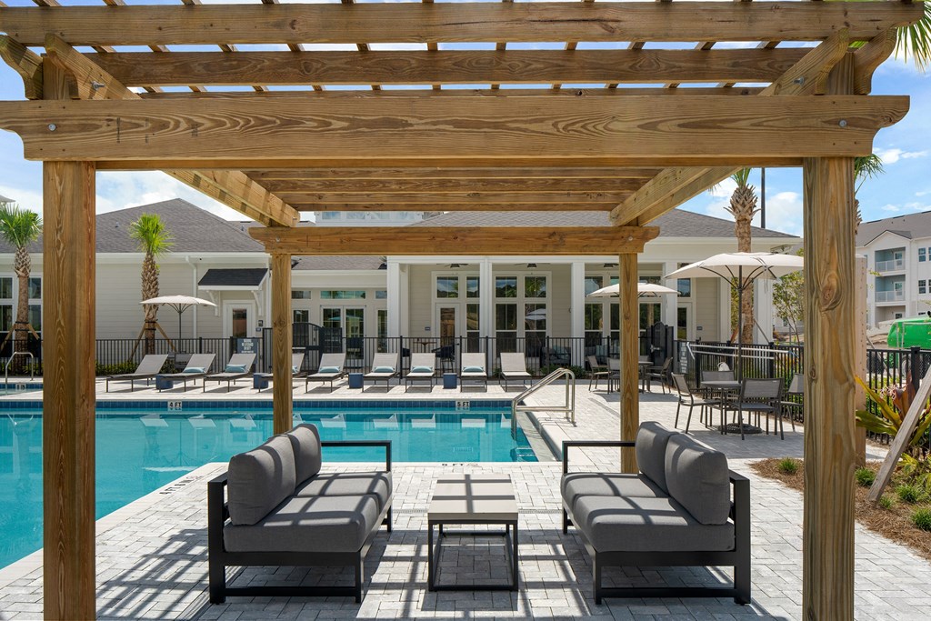 a resort style pool with lounge chairs and a pergola